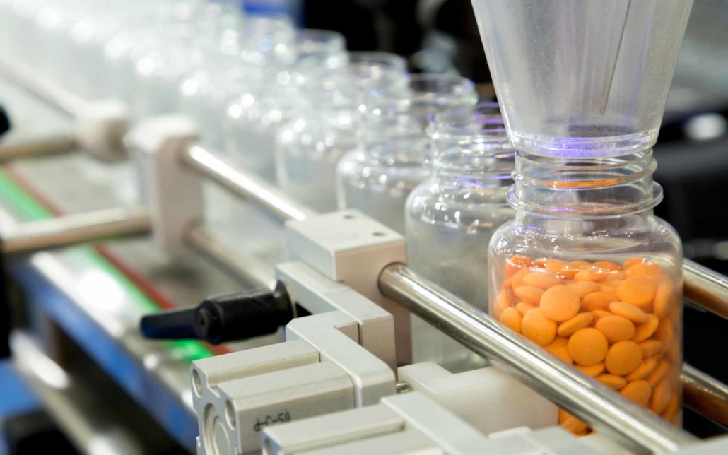 Close up view of orange pills being sorted into bottle